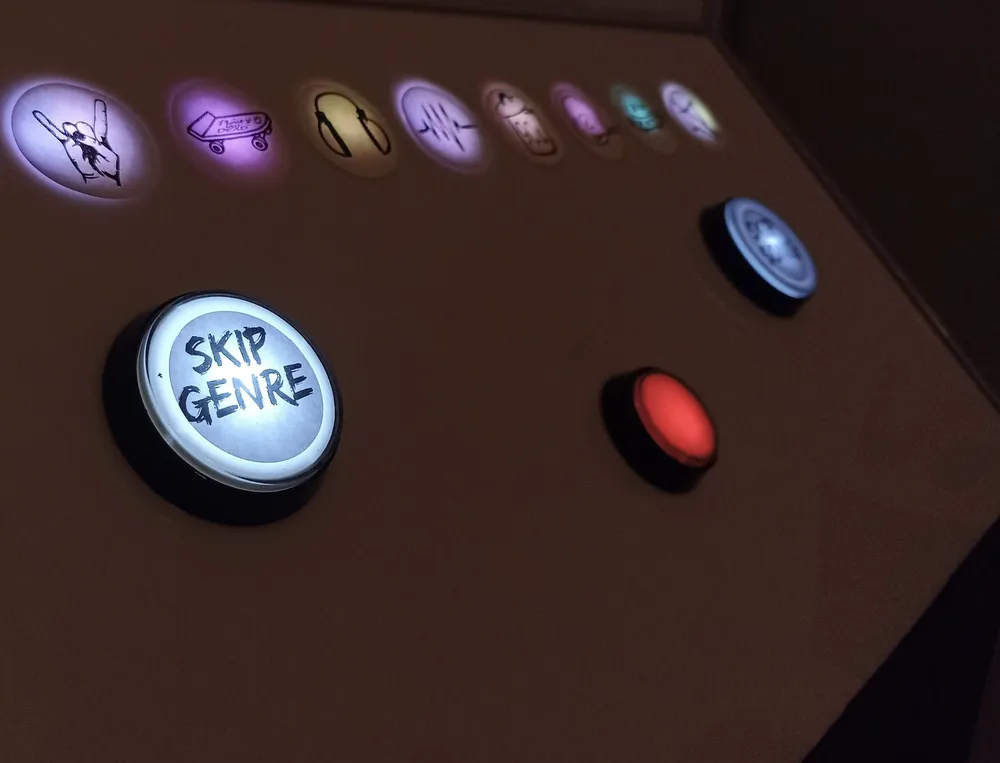 Leuchtende Buzzer und Genre-Symbole auf einem Automaten-Pult